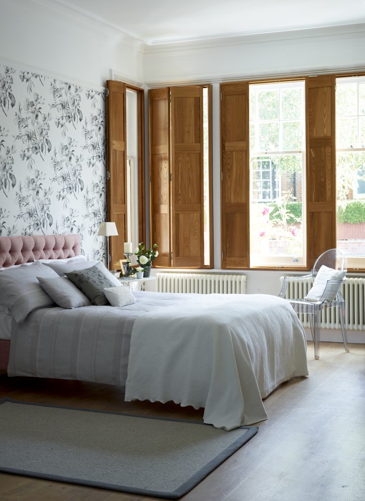 Solid bedroom shutters in a natural colour complementing a chic bedroom interior design.