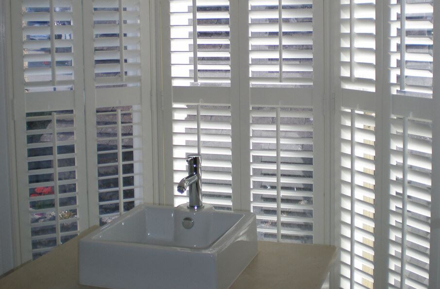 Full-height waterproof Salcombe shutters in a bay window with a small sink.