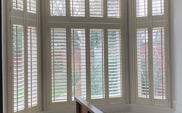 A closer view of bay window tier-on-tier shutters in white.