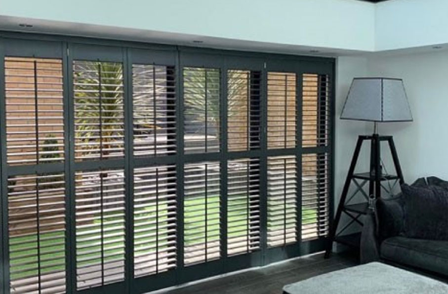 Black sliding patio door shutters in a modern room facing a garden