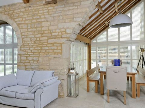 Special shape shutters in a rustic living room with an arched window and an apex window.