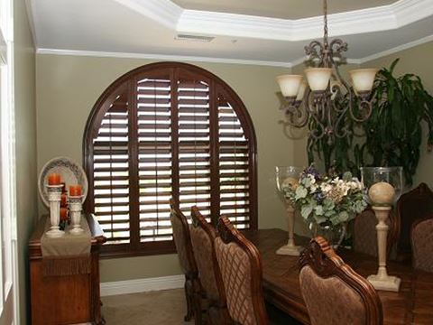 Arched dark wood window shutter in a rustic style dining room.