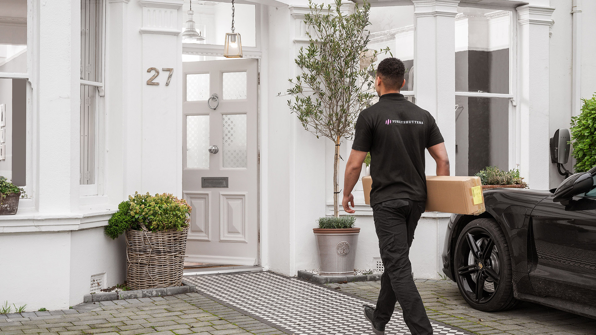 Purely Shutters employee carrying a box into a house