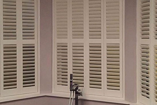A close up view of bay window shutters in a bathroom.