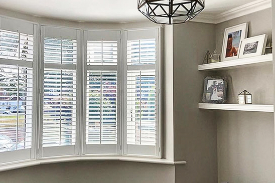White bay window shutters in a bright room.
