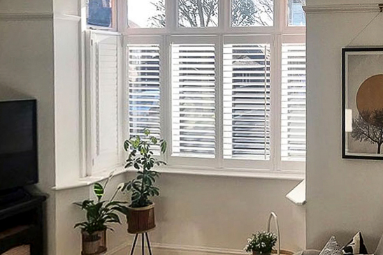 White shutters in a small study bay window.