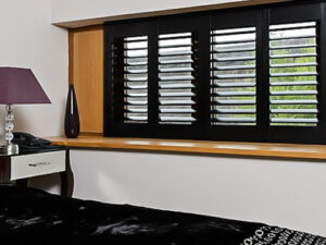 Black bedroom shutters in a bedroom with a black bed.