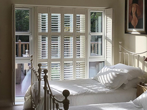 Bedroom shutters on a patio door in a rustic styled bedroom.