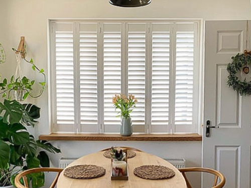Dining room full height shutters in a dining room with plants and bright colours.