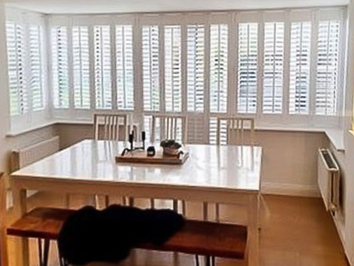 Dining room shutters on a large window in a bright dining room.