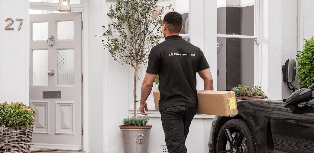 Purely Shutters employee carrying a box into a house